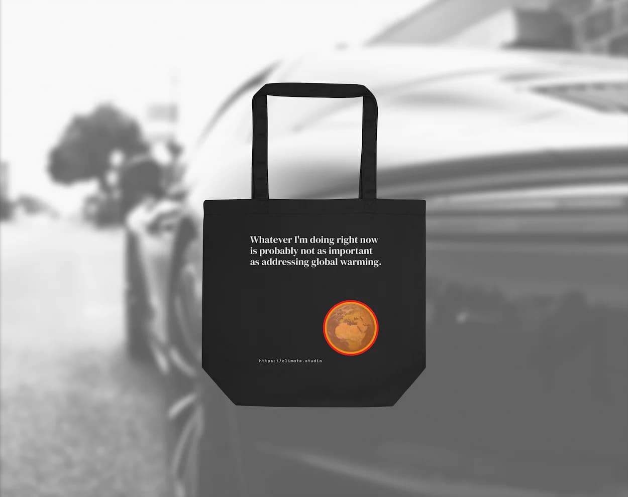 Black tote bag with climate message against car background